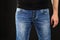 Close up of a man in classic blue jeans trousers and black shirt against black background. Male casual fashion concept with a