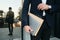 Close up man in classic suit and wristwatch holding laptop and big envelope in hand with reflection on background