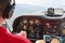 Close up of a man in a cockpit piloting small four seat airplane with hills and meadows in a distance