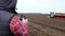 Close-up, man controls drone, Makes video how tractor works on farm field. Agriculturally potato cultivation, planting
