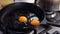 Close-up of man cooking fried eggs with chopped spinach in black cast-iron frying pan, selective focus