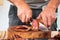 Close-up of a man cutting Iberian sausage on a wooden board