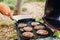 Close-up man flipping thick beef burgers frying on the grill outdoors