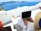 Close up of man hand Freelancer with laptop and running remotely with bright scenic view of the Mediterranean Sea and Santorini