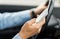 Close up of man hand with smartphone driving car