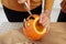 Close up of man hands carving Jack O Lattern from ripe orange pumpkin with knife on her wooden kitchen table. male