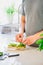 Close up man hands making a healthy meal of avocado toast and vegetables putting just picked greenery from homegrown