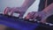 Close up man hands playing electric piano under colorful stage lighting