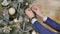 Close-up of man hanging decorative toy ball on Christmas tree branch