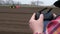 Close-up, man holds in hands remote control to drone, Makes video of tractor works on farm field. Agriculturally potato