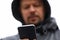 Close-up man in hood looks at display smartphone