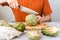 Close up Man with knife cutting artichoke on wooden cutting board on table. Cooking Healthy food and sliced vegetables