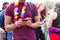 Close Up Of Man Looking At Mobile Phone As He Waits Behind Barrier At Entrance To Music Festival