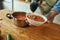 Close up of man pouring tasty soup from pot into bowl. Italian cook preparing traditional meal in the kitchen. Cooking