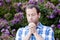 Close up of man praying alone in front of purple flowers.