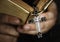 Close up of a man reading a bible with cross hanging religion and belief concept