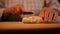 Close-up. A man rolls out dough with his hands on a wooden table. Then he uses a knife to cut the block of dough into