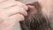 Close up of man`s bearded face. Man brushes his beard with hairbursh.