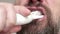 Close up of man`s bearded face who brushes his teeth with tooth brush and toohpaste.