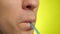 Close-up of a man`s face with a plastic straw, yellow background