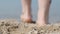 Close-up of a man`s feet on the beach, going into the water. Back view