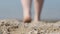 Close-up of a man`s feet on the beach, going into the water. Back view