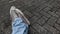 Close-up of a man's feet in jeans and casual shoes on the block floor