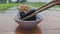 Close-up of a man's hand holding a sushi roll with chopsticks and dipping it in soy sauce, in a restaurant overlooking a