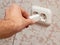 Close-up of a man`s hand inserting a charger plug into a wall outlet