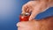 Close-up of a man\'s hand opening a red soda can on a blue background in slow motion. A can of red Cola opens.