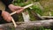 A close-up of a man's hand with a small camping axe chopping wood from planks. A hiker prepares wood chips for a