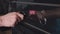 Close-up of a man's hand turning the handle of the oven. The man switches modes on the oven panel