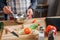 Close up of man`s hands blending eggs in bowl. He work at table in kitchen. Guy wear apron. Colorful vegetables and