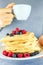 Close up of man`s hands holding waffles with berries and cup of coffee.