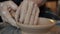 Close-up of man`s hands molding clay making bowl on spinning wheel in workshop