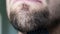 Close up man shaves beard on face with black razor. Unshaven man uses razor for shaving chin