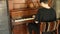 Close up of man sitting on an old wooden classic piano and playing music