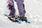 Close-up of man skier feet and legs in short plastic bright professional wide skis on white snow sunny copy space background.