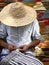 Close up man in straw hat mending carpets on sale, Essaouira, Morocco