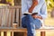 Close Up Of  Man With Takeaway Coffee Sitting On Park Bench Under Tree Writing In Notebook