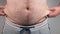 Close up of Man touching his fat belly, Men`s hand holding excessive belly fat. Being overweight is one of the leading