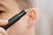 close-up. a man with trimmers for cutting hair in nose and ears. selective focus