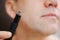 close-up. a man with trimmers for cutting hair in nose and ears. selective focus