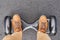 Close up of man using hoverboard on asphalt road. Feet on electrical scooter outdoor, top view