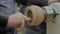 Close up: man using sandpaper for sanding piece of wood on lathe - slow motion