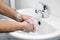 Close-up of a man washing his hands with soap suds and water over a white sink. Concept of prevention, protection and hygiene