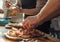 Close-up of a man and a woman& x27;s hands are preparing pizza in the kitchen in a restaurant, laying out the meat and oiling