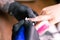 Close-up of manicurist woman removes gel shellac polish from client`s nails using manicure machine. Manicure master is