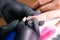 Close-up of manicurist woman removes gel shellac polish from client`s nails using manicure machine. Manicure master is