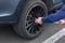 Close up mans hands changing a wheel using screwdriver. Replacing winter and summer tires. Seasonal tire replacement concept.